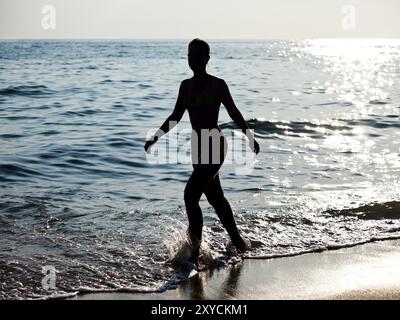 Vacances d'été, belle silhouette de femme mince marchant sur la plage de sable de mer Banque D'Images