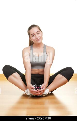 Femme étendant ses jambes assis sur le plancher, isolé en blanc Banque D'Images