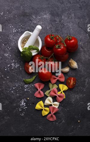 Pâtes farfalle colorés italienne, tomate et épices sur fond noir en ardoise noire Banque D'Images