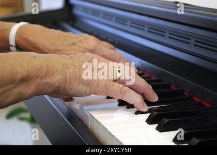 Les deux mains d'une femme âgée jouant du piano Banque D'Images