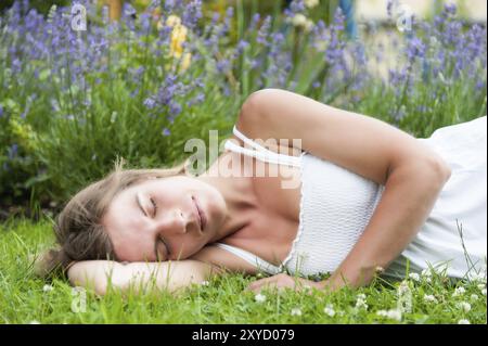 Portrait d'une belle jeune femme dans une robe d'été blanche couchée dans un pré devant la lavande fleurie. portrait d'une belle jeune femme dans un Banque D'Images