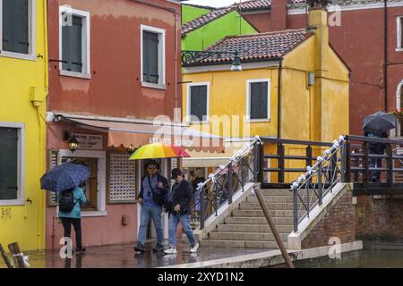 Vue sur la ville de Burano avec des maisons colorées et des canaux. Temps pluvieux, les gens portent des parapluies. Burano, Venise, Venise, Italie, Europe Banque D'Images