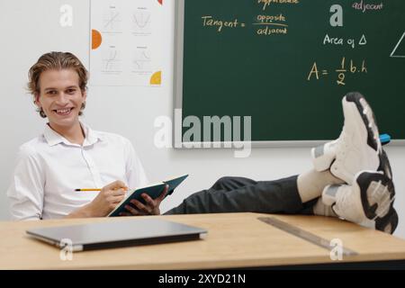 Portrait de professeur souriant assis avec Notebook dans la salle de classe Banque D'Images