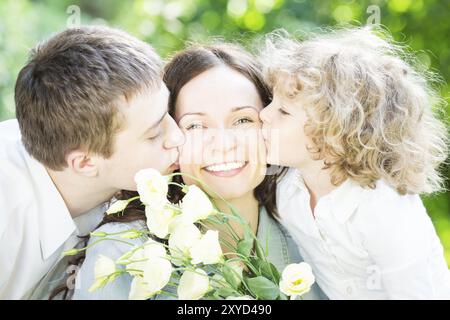 Famille heureuse ayant du plaisir à l'extérieur dans le parc de printemps sur fond vert nature. Concept de fête des mères Banque D'Images