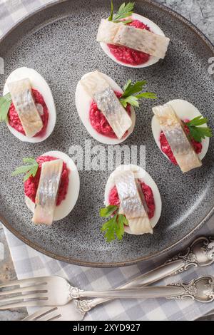 Gros plan d'œufs dévorés avec salade de betteraves et hareng dans une assiette sur la table. Vue de dessus verticale Banque D'Images