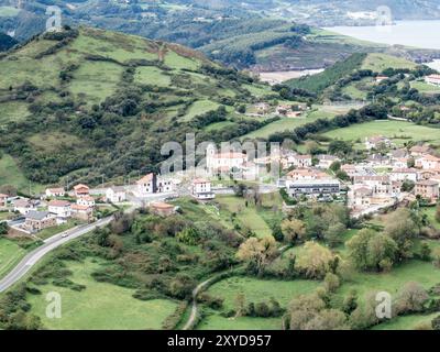 Vue sur un petit village niché entre Green Hills et campagne Banque D'Images