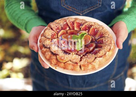 Des fig pie avec les noix et le miel dans les mains d'une femme Banque D'Images