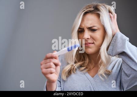 Doute, test de grossesse et gratter la tête avec une femme en studio isolé sur fond gris pour la maquette. Confus, questionnés et incertains avec la personne Banque D'Images