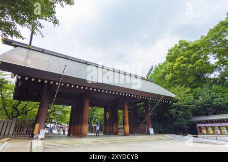 Tokyo, Japon, le 30 juillet 2015 : des gens marchent à travers la porte en bois Shinmon à l'entrée du controversé sanctuaire Shinto Yasukuni un jour sombre couvert. Banque D'Images