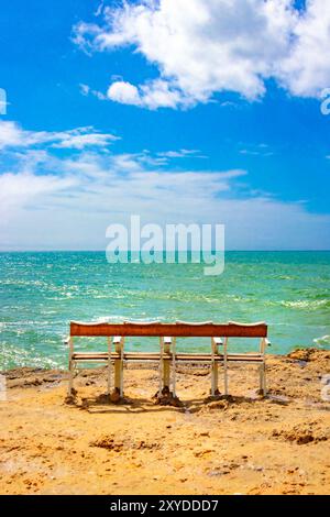 banc de quatre places vide face à la vaste mer turquoise scintillante par temps clair depuis une plage de sable. portugal Banque D'Images
