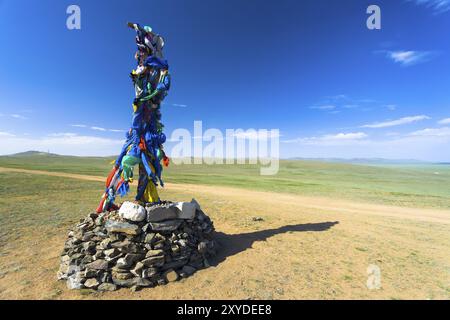 Petit stupa bouddhiste avec pierre drapeaux de prière se tient sur la grande steppe de la Mongolie à la campagne Banque D'Images