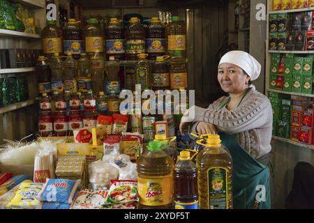 OSH, Kirghizistan, 05 octobre 2014 : une vendeuse de bouteilles d’huile posant pour la caméra dans sa boutique au bazar d’Osh, en Asie Banque D'Images