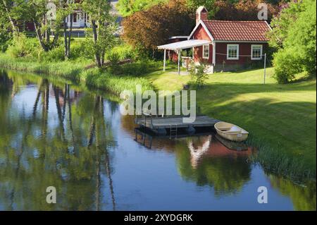 Maison traditionnelle suédoise en bois de couleur rouge cuivré sur les rives de la rivière Eman près de Hoegsby, Smaland, sud de la Suède. Vieille maison en bois rouge en t Banque D'Images