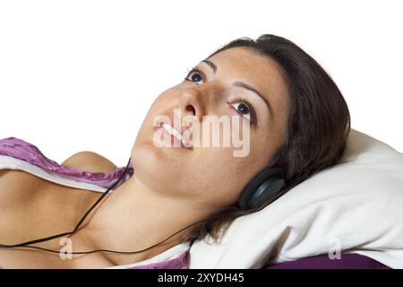 Portrait rapproché d'une jolie jeune femme couchée sur un pouf et écoutant de la musique à travers des écouteurs. Franco-italien européenne caucasien femelle Mo Banque D'Images