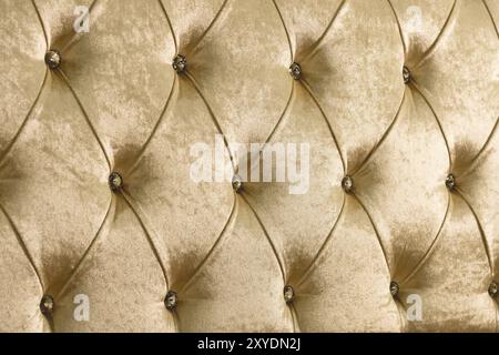 Fond textile doux beige avec boutons symétriques sur les coins des diamants. Eléments de mobilier doux et coûteux. Fond de luxe Banque D'Images