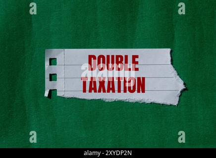 Message de double imposition écrit sur du papier déchiré déchiré avec fond vert. Symbole conceptuel de la double imposition. Copier l'espace. Banque D'Images
