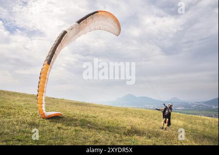 Le parapente ouvre son parachute avant de décoller de la montagne dans le Caucase du Nord. Remplissage de l'aile du parachute avec de l'air avant le décollage Banque D'Images