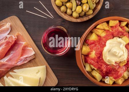 Des tapas espagnols. Jambon, fromage, vin, olives, et patatas bravas bravas, pommes de terre, tiré par le haut sur un fond foncé Banque D'Images