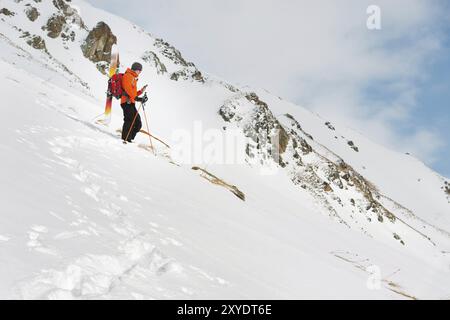 Un freerider de ski debout sur une pente dans une profonde poudreuse de neige photographie le paysage sur son téléphone portable avec l'équipement sur son dos, fixé sur un dos Banque D'Images