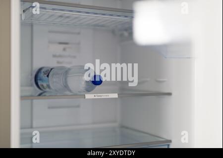 Une seule bouteille d'eau se trouve dans un réfrigérateur autrement vide Banque D'Images