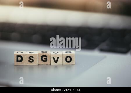 Cubes en bois avec les lettres DGSVO pour le Règlement général sur la protection des données reposent sur un ordinateur portable Banque D'Images