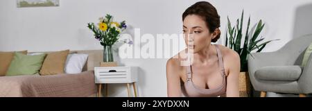 Une belle femme asiatique dans un crop top pratique le yoga et la méditation à la maison dans un appartement moderne. Banque D'Images
