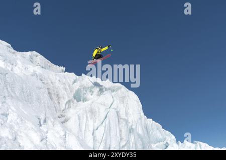 Un skieur sautant d'un glacier contre un ciel bleu haut dans les montagnes. Ski professionnel Banque D'Images