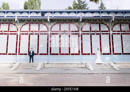 Les nouveaux mariés se tiennent séparément sur le fond de l'ancienne galerie d'exposition sur différents bords du cadre le concept d'une promenade de mariage et f Banque D'Images