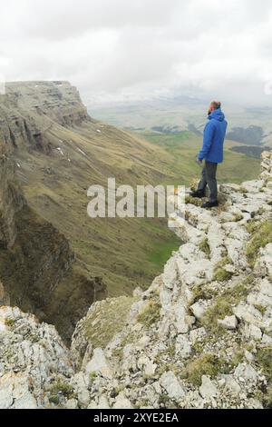 Touriste hipster barbu debout sur le bord d'un rocher et regardant au loin sur un plateau épique. Le concept de tourisme Banque D'Images