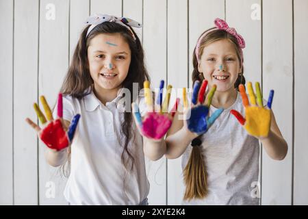 Portrait souriant deux filles montrant des mains peintes colorées regardant la caméra Banque D'Images