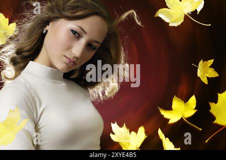 Jeune belle femme expressive portrait romantique dans un tourbillon de feuilles d'érable d'automne jaune sur fond rouge foncé Banque D'Images