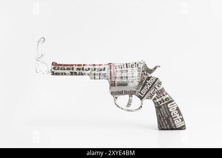 Revolver collé avec les titres d'un journal, image symbolique Banque D'Images