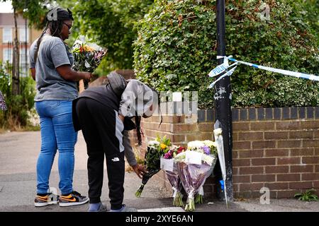 Des membres du public rendent hommage à des motifs floraux sur Overbury Street, près de la scène à Rushmore Road, Clapton, à l'est de Londres, après qu'un homme de 30 ans ait été poignardé à mort. Deux hommes ont été arrêtés. Date de la photo : jeudi 29 août 2024. Banque D'Images