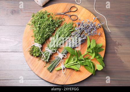 Différentes herbes aromatiques et ciseaux sur table en bois, vue de dessus Banque D'Images