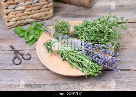 Différentes herbes aromatiques et ciseaux sur table en bois Banque D'Images