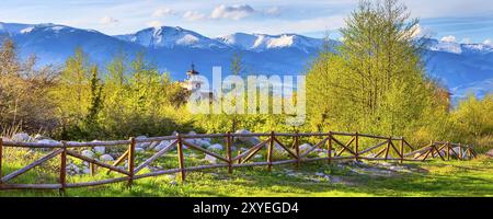 Bansko, Bulgarie paysage de printemps avec la clôture en bois, arbres, tour de chalet et sommets enneigés de Rila Banque D'Images