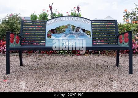 Banc commémoratif noir sur pierre libre au mémorial de guerre local, dessin au dos représentant le HMS Belfast C35, 1938. Ballycastle, Royaume-Uni - 24 août 2024. Banque D'Images