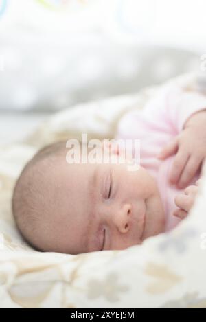 Nouveau-né endormi. Mignonne petite fille d'une semaine à la maison. Adorable couché sur le côté couvert de couverture. Pas de retouche, peau sèche du nouveau-né Banque D'Images