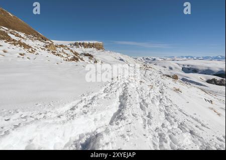 Le paysage de rochers caucasiens enneigés sur le col de Gumbashi. Plateau enneigé passant dans la montagne de la table avec un sentier de neige à l'avant Banque D'Images