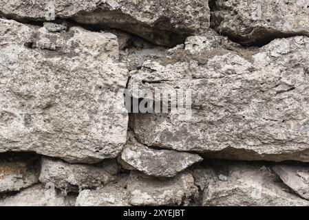 Le fond texturé en gros plan est un mur irrégulier en pierre naturelle fait de différentes pierres sans mélange de liaison de type ciment. Fond médiéval Banque D'Images