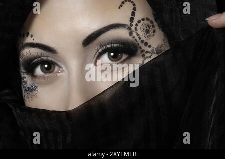 Visage de femme exotique avec art de tatouage temporaire artistique recouvert d'un foulard noir Banque D'Images