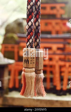 Corde d'un Suzu, cloche du sanctuaire shinto japonais avec offrande écrite dessus au sanctuaire Fushimi Inari à Kyoto, Japon, Asie Banque D'Images