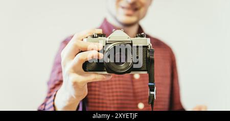 Jeune homme en chemise à carreaux rouge-bleu est de prendre une photo avec un appareil photo, vintage retro style Banque D'Images