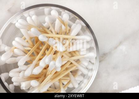 Un passage photo gros plan de bambou coton-tiges dans un bocal de verre sur une surface en marbre avec copyspace Banque D'Images