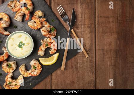 Crevettes frites avec une sauce caesar et citron, tourné par le haut sur un fond de bois rustique foncé avec une place pour le texte Banque D'Images