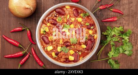 Un panorama de chili con carne, tourné par le haut sur un fond de bois rustique foncé avec des ingrédients Banque D'Images