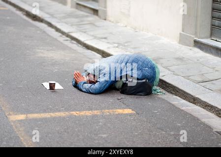 Femme mendiante couchée dans la rue Banque D'Images