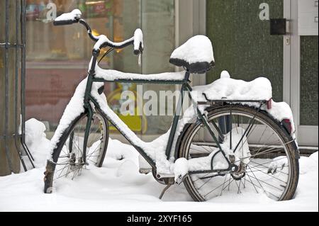 Bicyclette enneigée devant une porte d'entrée Banque D'Images