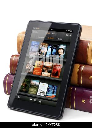 Amazon Kindle Fire tablette e-book appuyé contre une pile de livres à couverture rigide. Isolé sur fond blanc Banque D'Images