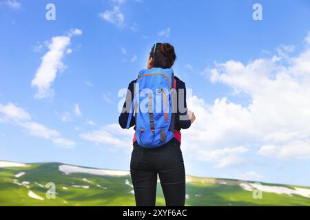 Hiker with backpack se détendre au sommet d'une montagne et profiter de la vallée durant le lever du soleil Banque D'Images